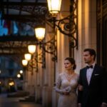 Stylový pár opouští operu za soumraku, osvětlení od reflektorů a lamp vytváří teplou atmosféru.