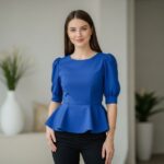 Mladá žena v moderním interiéru nosí halenku peplum zdůrazňující postavu, jemné přirozené osvětlení.